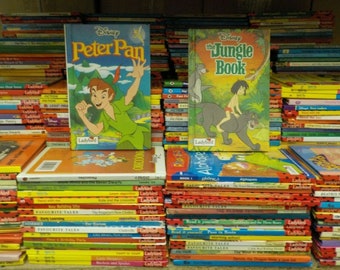 May include: A stack of Ladybird books featuring Disney's Peter Pan and The Jungle Book. The books are arranged in a colorful display with red, yellow, and blue covers. The books are all paperback and have a Ladybird logo on the front.