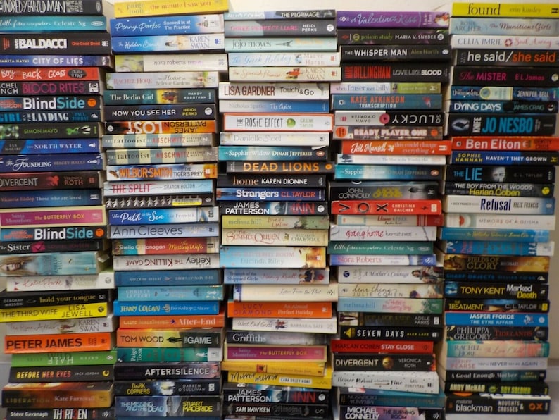 May include: A large collection of paperback books stacked in two columns. The books are mostly fiction and feature a variety of authors and titles. Some of the titles include "Blindside", "The Split", "The Boy from the Woods", "Divergent", "Ready Player One", "The Lie", "The Third Wife", "After-End", "Seven Days", "Before Her Eyes", "After Silence", "The Butterfly Effect", and "The Bookman".