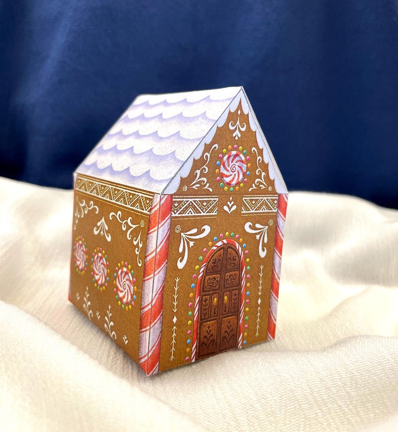 May include: A paper gingerbread house with brown walls, white frosting, and red and white candy cane stripes. The roof is white with purple accents. The house is decorated with candy and swirls.