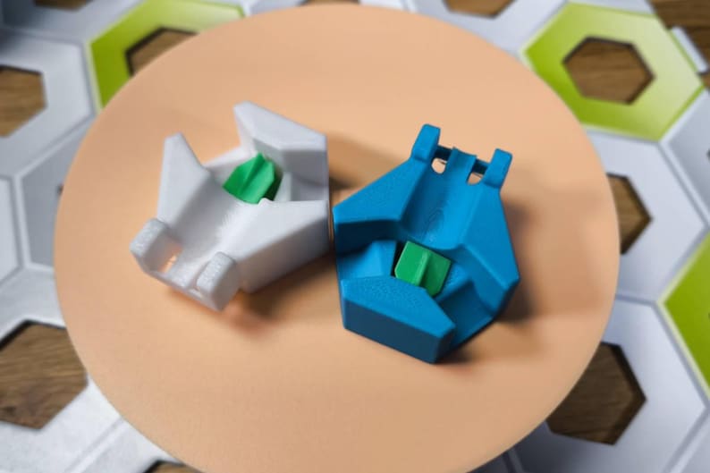May include: Two 3D printed keycaps, one white and one blue, with a green accent piece in the center of each. The keycaps are designed to fit on mechanical keyboards.