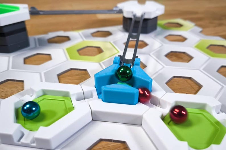 May include: A blue and white marble run game with a green, red, and blue marble. The blue marble is being lifted by a lever.