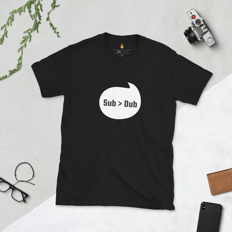 Puede incluir: Camiseta negra con un gr&aacute;fico de burbuja de di&aacute;logo blanca que dice "Sub > Dub".