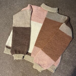 May include: A knitted sweater with a color block design in shades of brown, pink, and cream.