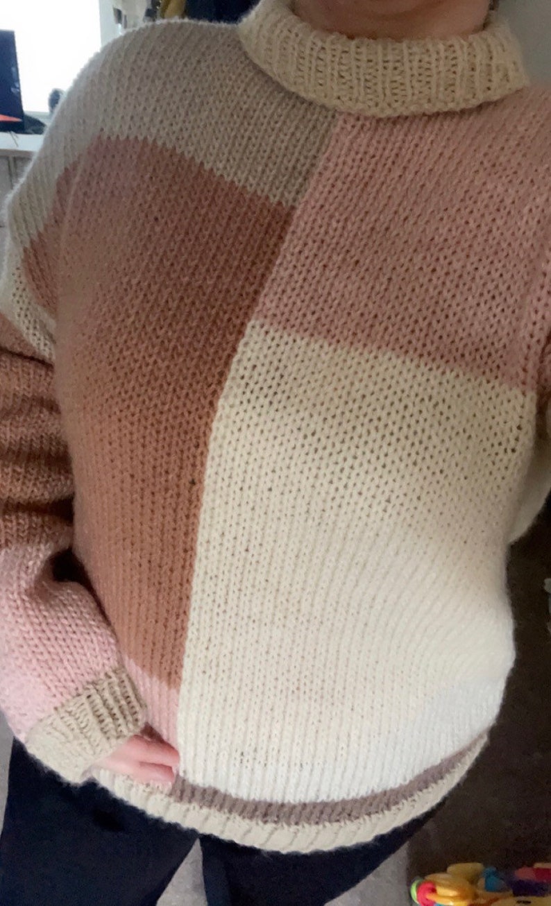 May include: A chunky knit sweater with a color block design in shades of pink, brown, and white.