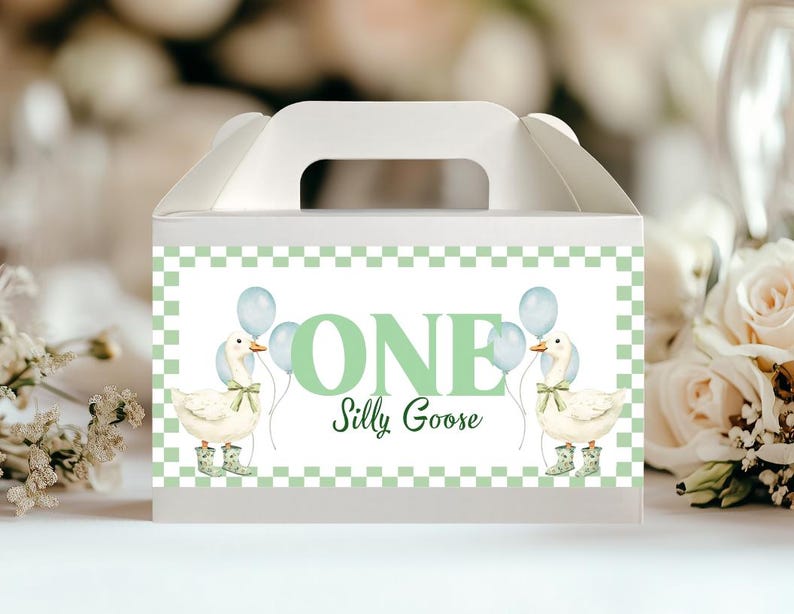 May include: White favor box with a handle, featuring a green and white checkered border. The box displays the text "ONE Silly Goose" with illustrations of geese holding balloons. The geese wear wellington boots.