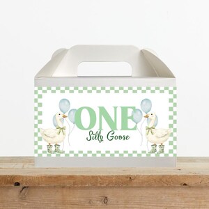 May include: White gable box with a handle, featuring a green and white checkered border. The box displays the text "ONE Silly Goose" with illustrations of geese holding balloons. The geese wear boots and bows.