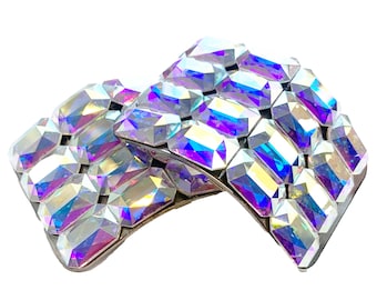 May include: Two iridescent crystal hair clips with a silver base. The clips are made of faceted crystals that reflect light in a rainbow of colors.