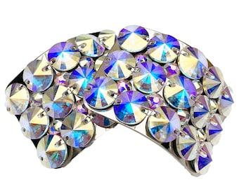 May include: Two silver-toned hair clips adorned with iridescent blue and clear rhinestones. The clips are curved and have a rounded shape.