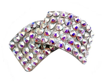 May include: A silver hair clip with a design of iridescent rhinestones arranged in a geometric pattern.