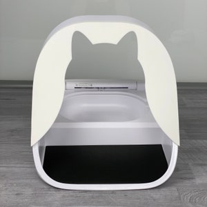 May include: White automatic self-cleaning cat litter box with a black litter tray and a cat-shaped opening.