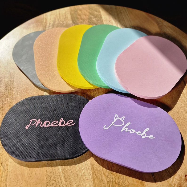 May include: A set of 10 colorful round coasters with the word "Phoebe" written on two of them. The coasters are made of a soft, spongy material and are perfect for protecting surfaces from scratches and spills.