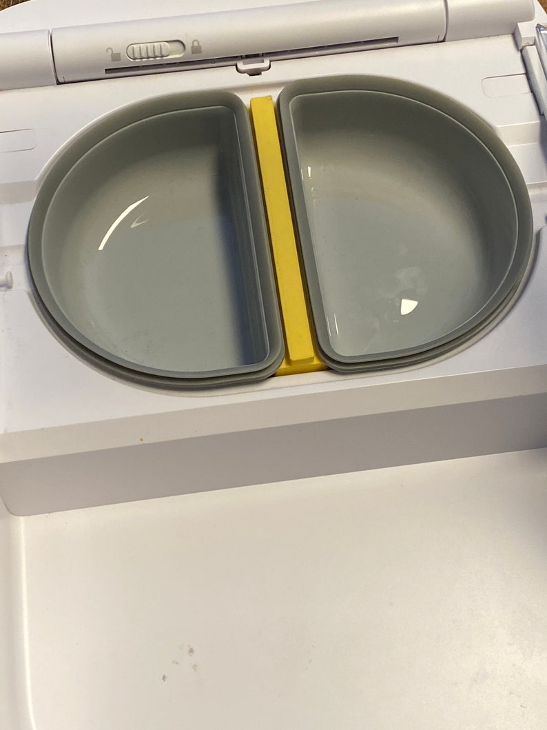 Peut inclure: Une bo&icirc;te &agrave; lunch en plastique blanche avec deux compartiments gris et une cloison jaune. Le couvercle a un loquet.