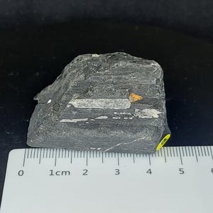 Raw black tourmaline mineral specimen with layered texture and organic form