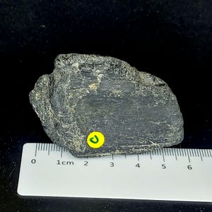 Black tourmaline rough rock photographed from angled view showing natural formation