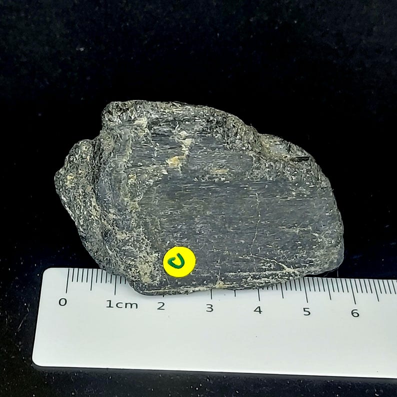 Black tourmaline rough rock photographed from angled view showing natural formation