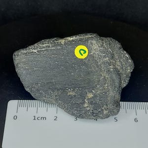 Black tourmaline raw crystal photographed on dark background highlighting texture