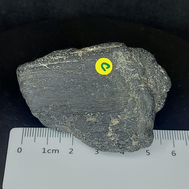 Black tourmaline raw crystal photographed on dark background highlighting texture