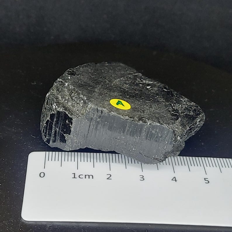 Raw black tourmaline crystal specimen showing natural texture and unpolished surface