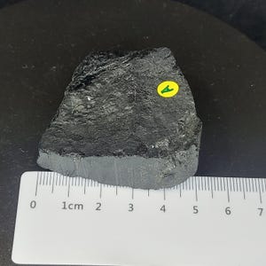 Black tourmaline rough rock side view with visible natural fractures and matte finish