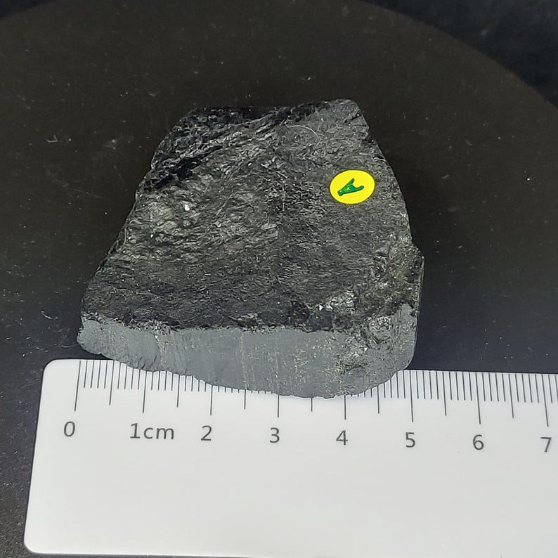 Black tourmaline rough rock side view with visible natural fractures and matte finish