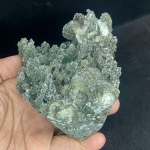 Handheld green chalcedony druzy calcite specimen showing size reference