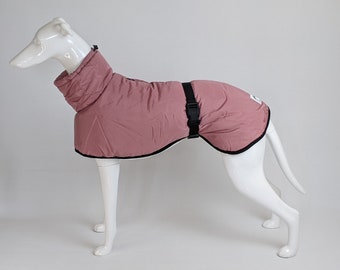 May include: A dusty rose dog coat featuring a high collar with a drawstring toggle, a black adjustable waist strap with a plastic buckle, and black trim along the edges. A small rectangular white label is visible on the rear of the garment.