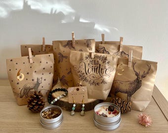 Puede incluir: Un conjunto de bolsas de papel marrón con temática invernal. Las bolsas están decoradas con ilustraciones de animales, copos de nieve y el texto "Hello Winter". También hay algunos artículos decorativos pequeños, como una piña, una vela y un par de pendientes.