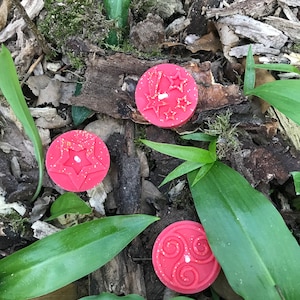Op de afbeelding: Drie rode wax melts met verschillende ontwerpen. De eerste kaars heeft een stervormig ontwerp, de tweede kaars heeft een swirl-ontwerp en de derde kaars heeft een stervormig ontwerp met glitter.