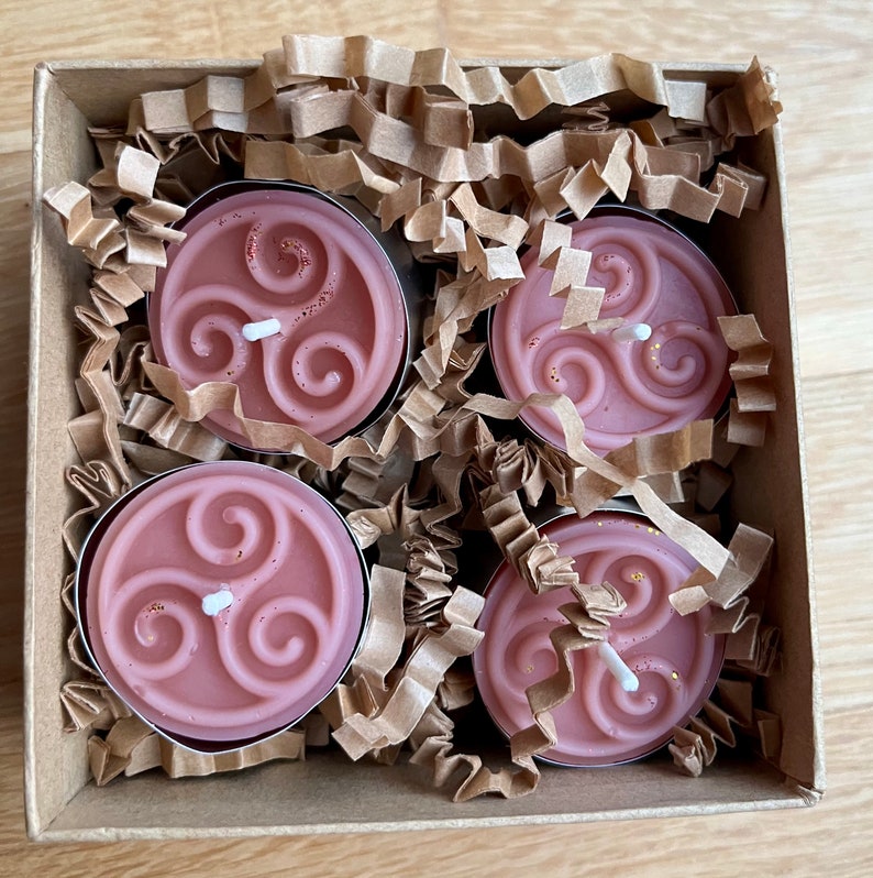 May include: Four pink tea light candles with a Celtic knot design in a brown cardboard box with shredded paper.