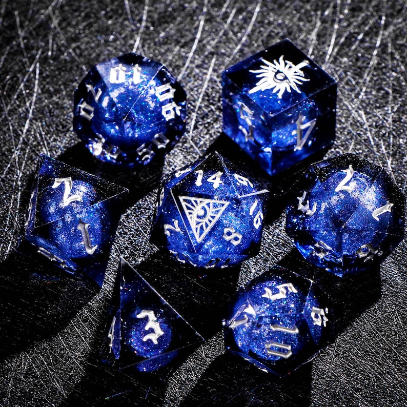 May include: Set of seven polyhedral dice in shades of blue with silver numbering and symbols. The dice are transparent with a galaxy-like effect inside. The dice are for tabletop role-playing games.