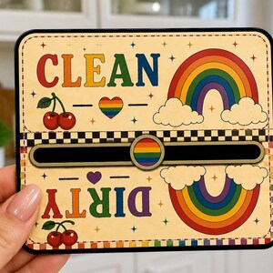 May include: A rectangular dishwasher magnet with a cream background, featuring a sliding indicator. The top half displays the word CLEAN in rainbow letters, cherries, a rainbow, and a heart. The bottom half shows DIRTY in rainbow letters.