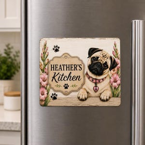 May include: A rectangular refrigerator magnet featuring a fawn-colored pug wearing a pink collar with a heart-shaped tag. The design includes pink gladiolus flowers, black paw prints, and a central plaque with the text Heather's Kitchen.