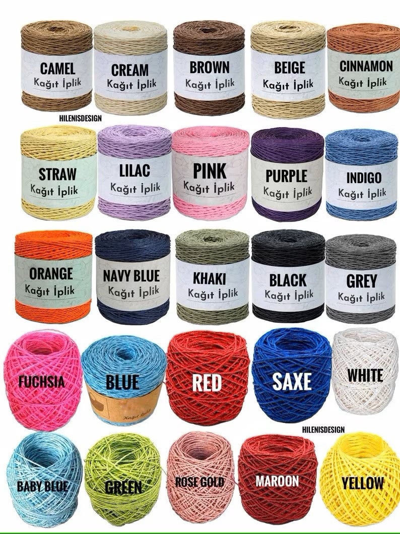 May include: A collection of twenty-five spools and balls of paper yarn in various colors including camel, cream, brown, beige, cinnamon, straw, lilac, pink, purple, indigo, orange, navy blue, khaki, black, grey, fuchsia, blue, red, saxe, white, baby blue, green, rose gold, maroon, and yellow.