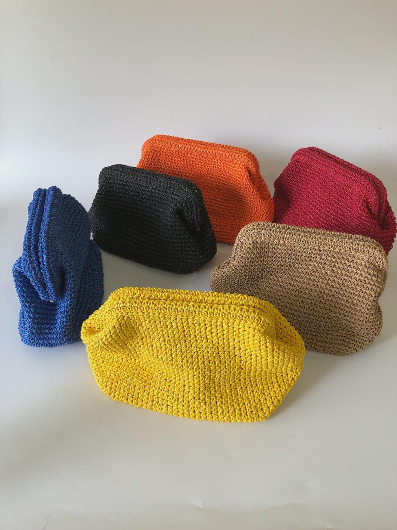 Puede incluir: Una colecci&oacute;n de seis bolsos peque&ntilde;os y rectangulares hechos de material tejido en colores vibrantes que incluyen azul, negro, naranja, rojo, beige y amarillo. Cada bolso presenta una abertura de marco estructurado y una superficie texturizada.