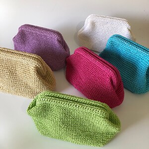 May include: A collection of six small, rectangular crochet pouches with kiss-lock closures. The pouches are available in a variety of solid colors including lime green, beige, purple, white, bright pink, and turquoise, each featuring a textured weave.