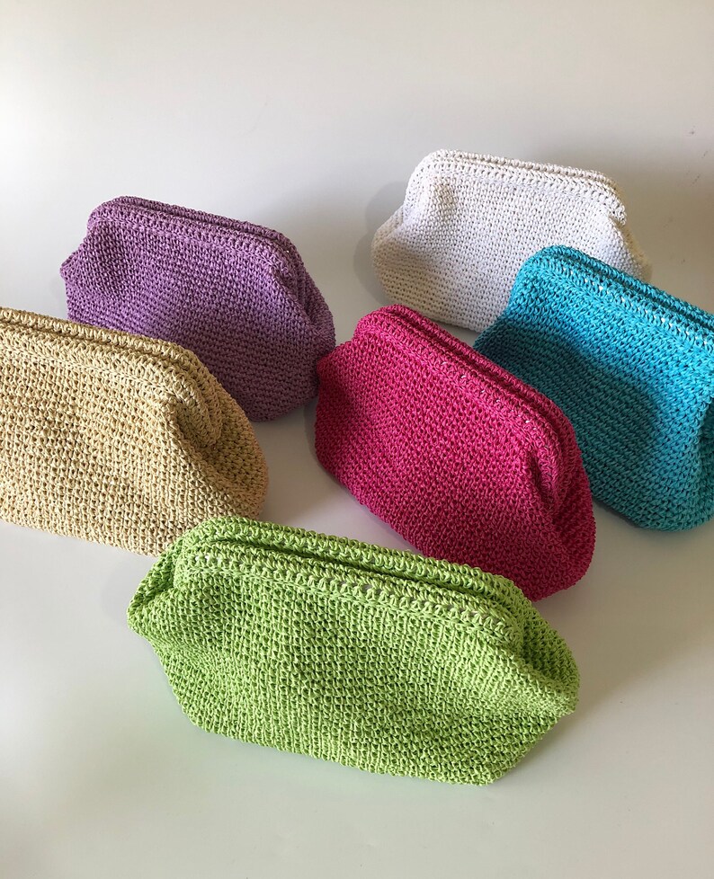May include: A collection of six small, rectangular crochet pouches with kiss-lock closures. The pouches are available in a variety of solid colors including lime green, beige, purple, white, bright pink, and turquoise, each featuring a textured weave.