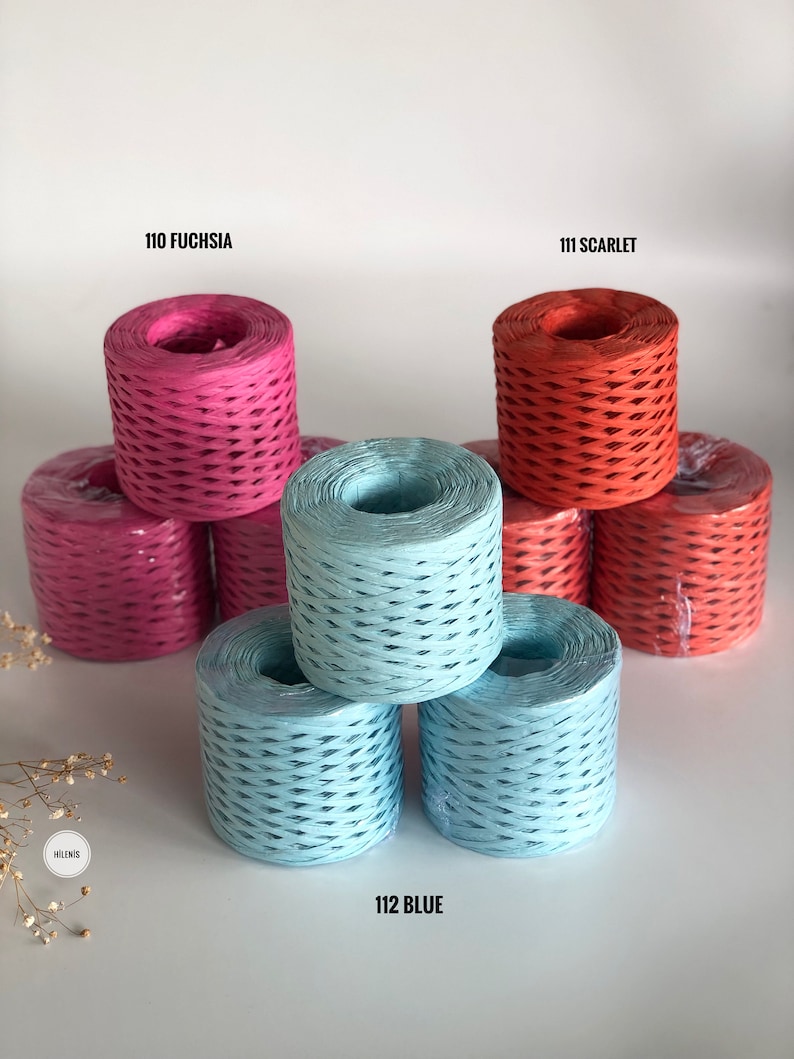May include: Three spools of paper cord, one fuchsia, one scarlet, and two light blue. The spools are stacked on a white surface.