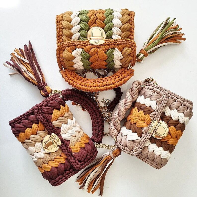 May include: Three crocheted handbags in brown, beige, and green with gold clasps. The bags have a woven pattern and are decorated with tassels.