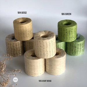 May include: Three spools of paper twine in beige and green. The spools are stacked on a white surface. The spools are labeled 104 Beige, 105 Light Beige, and 106 Green.
