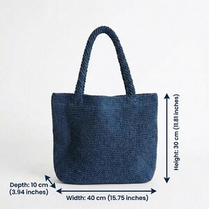 May include: A dark blue woven tote bag with two braided handles. The bag measures 15.75 inches in width, 11.81 inches in height, and 3.94 inches in depth. The texture is consistent throughout the body and handles, featuring a dense, uniform weave.