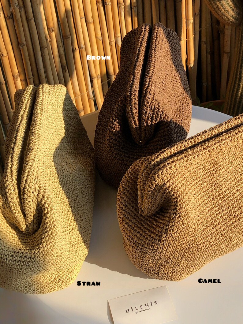Puede incluir: Tres bolsos estructurados con textura tejida, cada uno en un color distinto: paja, marr&oacute;n y camel. Los bolsos tienen una apertura de marco con bisagras. Una peque&ntilde;a tarjeta blanca con el texto HILENIS se encuentra en la parte inferior.
