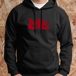 May include: Black hooded sweatshirt with a front pocket and red "LOVE" text. The word "LOVE" is in a decorative font. The sweatshirt is made of a soft material and has a drawstring hood.