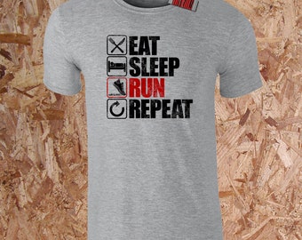 May include: A heather gray t-shirt with the words "EAT SLEEP RUN REPEAT" printed in black and red. The design includes icons representing eating, sleeping, running, and repeating. A small tag with a barcode is attached to the shirt.