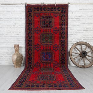 May include: A long rectangular rug featuring a vibrant red background with a dark blue border and four central geometric medallions in shades of blue, green, and red. The rug displays intricate repeating patterns throughout the field.