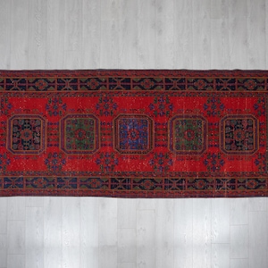 May include: A rectangular area rug featuring a vibrant red background with five prominent dark blue and green geometric medallions. The rug is framed by a wide, dark blue border decorated with repeating black and red linear patterns.