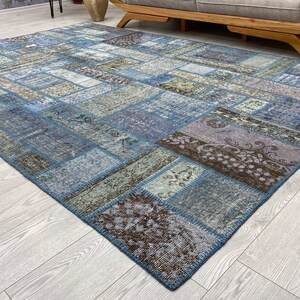 May include: A patchwork rug with a blue, brown, and beige color scheme. The rug is made of different pieces of fabric sewn together to create a unique design.