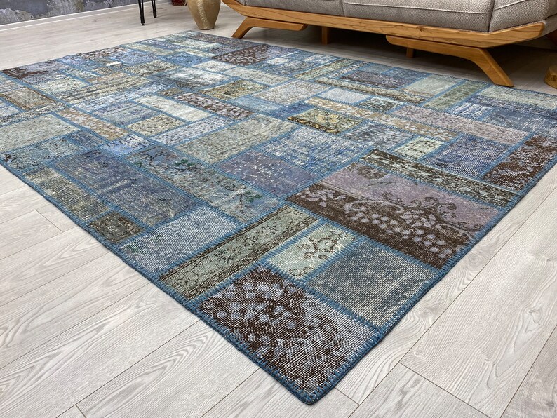 May include: A patchwork rug with a blue, brown, and beige color scheme. The rug is made of different pieces of fabric sewn together to create a unique design.