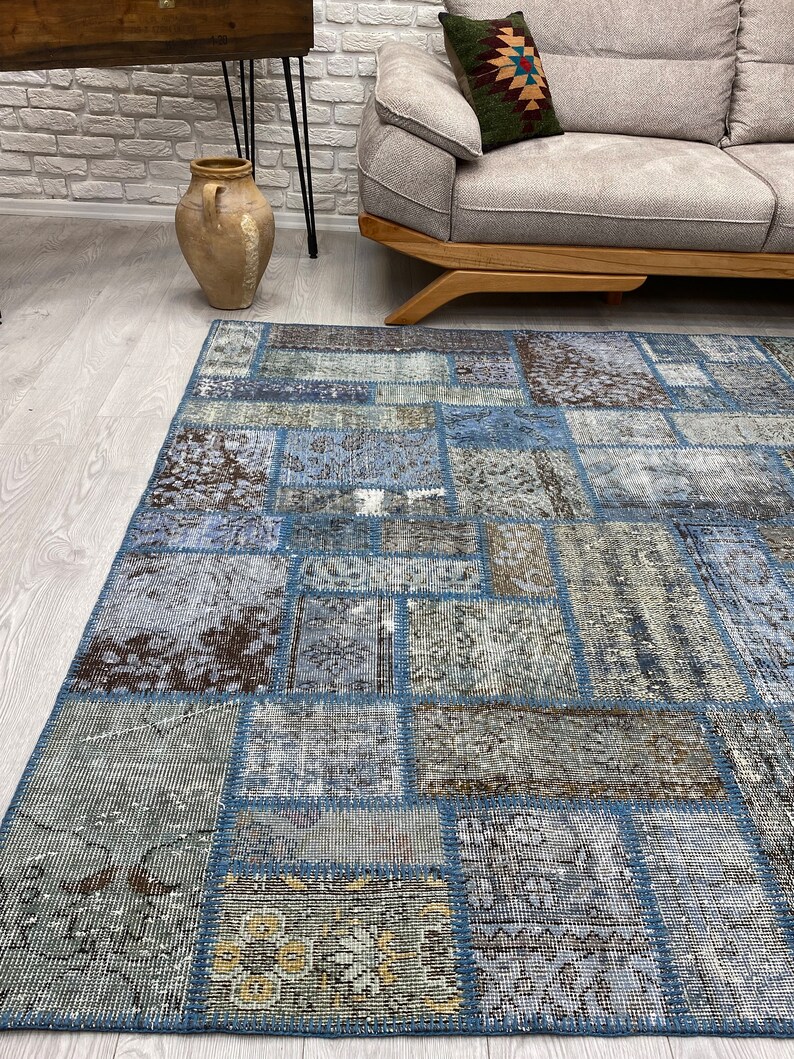 May include: A blue and brown patchwork rug with a distressed look. The rug is made of different pieces of fabric sewn together.