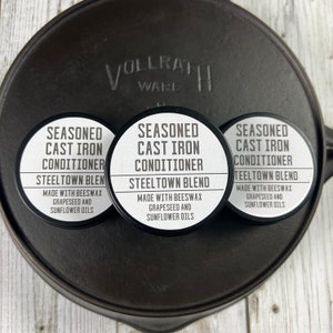 May include: Three round containers of cast iron conditioner. Each container has a black and white label that reads "Seasoned Cast Iron Conditioner" and "Steeltown Blend". The label also states "Made with Beeswax, Grapeseed and Sunflower Oils".