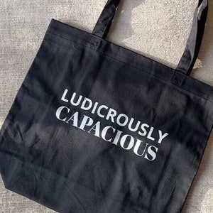 May include: A black canvas tote bag with white text that reads "Ludicrously Capacious".